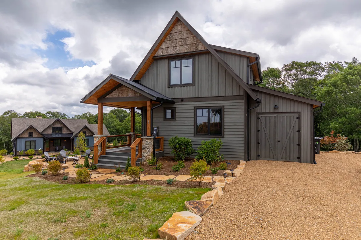A wide, inviting view of the front porch and landscaped garden, featuring exterior wood details and stone accents. This setting hints at ample space for outdoor gatherings, relaxing with pets, and easy access to nature trails just beyond the property.