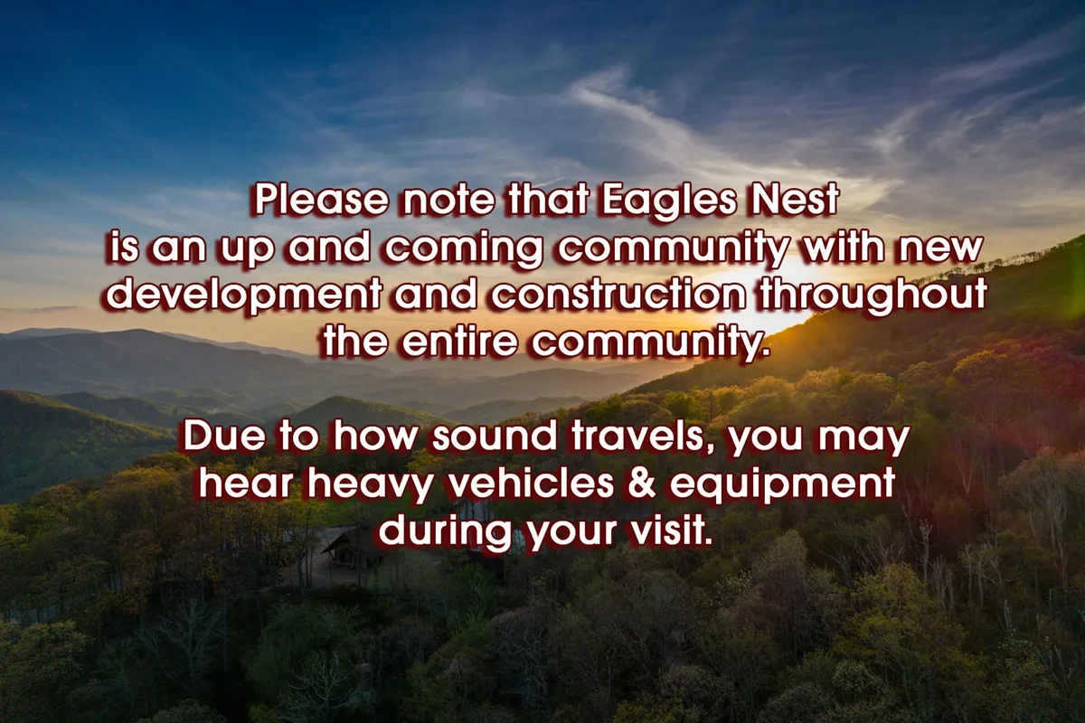 A stunning panoramic view of a mountain range under a colorful sunset sky, framed by a lush tree line. The scene radiates tranquility and showcases the breathtaking natural beauty that surrounds Eagles Nest, inviting families to explore the outdoors.