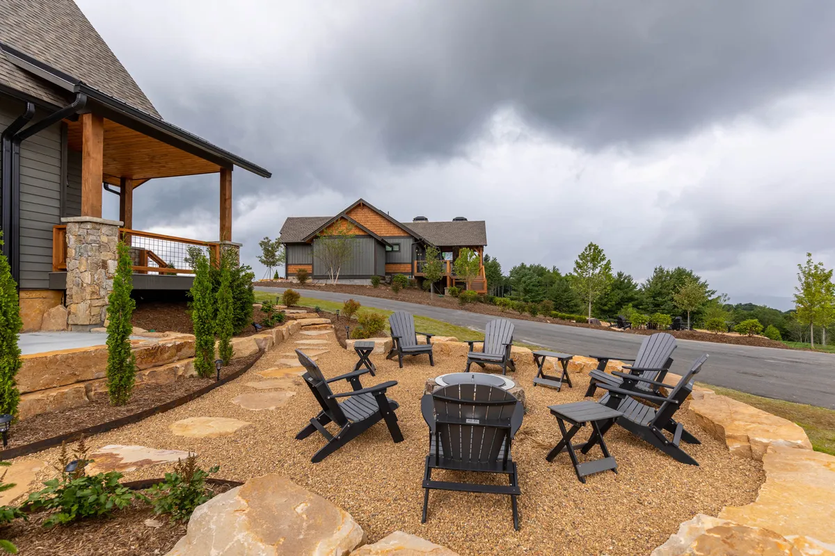 A cozy exterior fire pit area surrounded by inviting chairs and lush landscaping. The setting is communal and relaxed, with a clear emphasis on gathering, stargazing, and socializing in a resort-like outdoor environment.